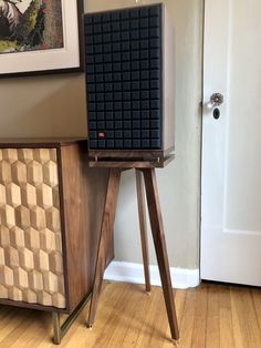 a wooden table with a black box on it next to a white door and some pictures