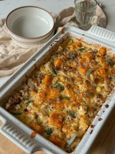 a casserole dish with meat and vegetables in it next to a glass bowl