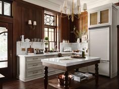 a large kitchen with wooden floors and white cabinets, an island in front of the sink