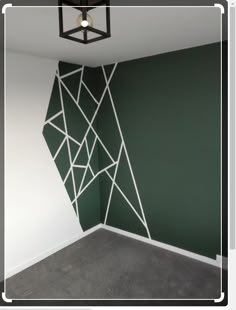 an empty room with green walls and white lines on the wall, in front of a light fixture