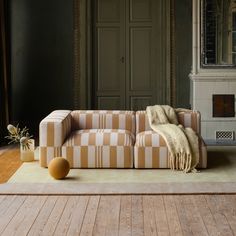 a striped couch sitting on top of a hard wood floor next to a fire place