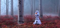 a snowman sitting in the middle of a forest with red leaves on the ground