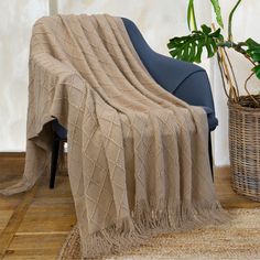 a chair with a blanket on it next to a potted plant