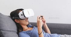 a woman laying on a couch wearing a virtual reality headset - stock photo - images