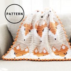 an orange and white crocheted blanket sitting on top of a couch