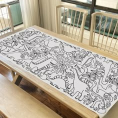 a dining room table with an intricately designed placemat on it, in front of a window