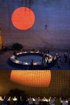 people are gathered around a circular table in front of an orange and blue circle on the wall