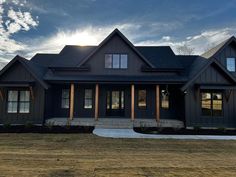 a large black house sitting on top of a grass covered field