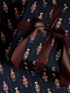 a gift wrapped in black wrapping paper with nutcrackers on it and a red ribbon