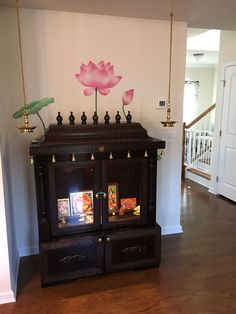 a living room with a large wooden cabinet and flowers on the top shelf, in front of a staircase