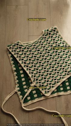 a green and white crocheted blanket sitting on top of a wooden floor next to a