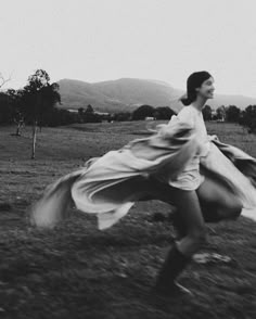 a woman is running in the grass with her dress flowing over her body and head