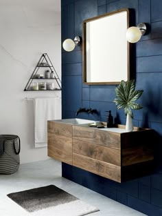 a bathroom with blue walls and wooden furniture, including a mirror over the sink that is hanging on the wall