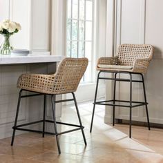 two wicker barstools sit in front of a counter with flowers on it