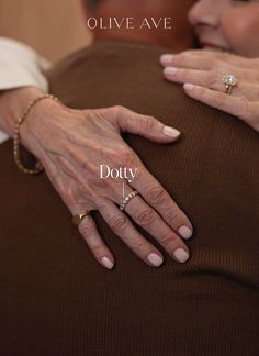 an older woman's hands resting on the back of her husband, who is wearing a diamond ring