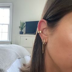 a close up of a person wearing earring in a room with a bed and window