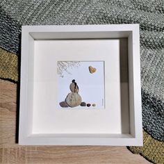 a white frame with a painting of a bird sitting on a rock