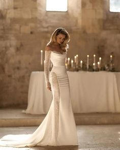 a woman in a wedding dress standing next to a table with candles