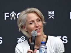 a woman holding a microphone in front of a black wall with the words focus on it