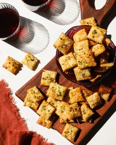 some food is sitting on a plate next to two glasses of wine and a wooden cutting board