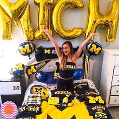 a woman is sitting on her bed in front of some gold balloons and black and yellow decorations