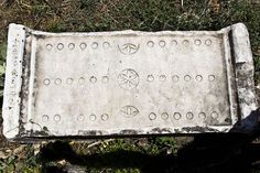 an old cement sign with circles and arrows on it in the grass near some bushes