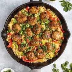 a skillet filled with meatballs and vegetables on top of a white countertop