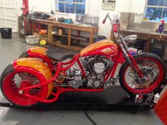 an orange and red motorcycle is parked in a garage with other tools on the table