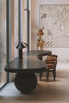 a table and chairs in a room next to a wall with an abstract painting on it