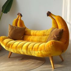 a banana shaped chair with two pillows on it's back and legs, sitting in front of a potted plant