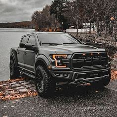 a black truck parked next to a body of water