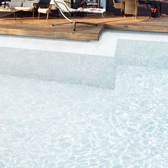 an empty swimming pool with lounge chairs and umbrellas on the deck next to it