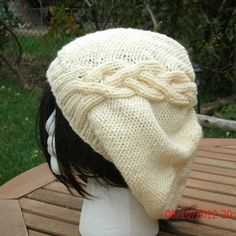 a white knitted hat sitting on top of a wooden table