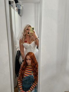 two women dressed as brides taking selfies in a mirror