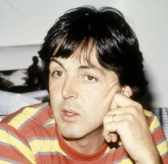 a man in striped shirt holding his hand to his ear