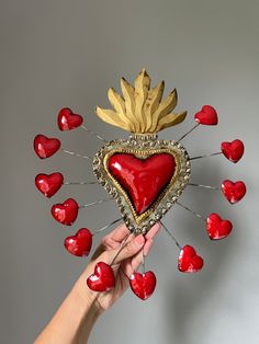 a hand holding a heart shaped object with lots of red hearts around it on a gray background