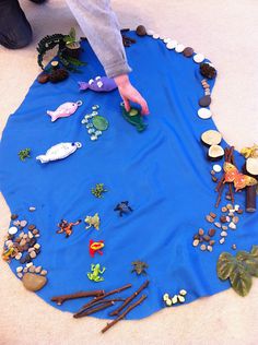 a child is playing with toys on the floor in front of a blue rug that has fish and rocks all over it