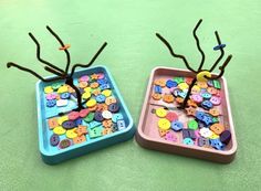 two plastic trays filled with buttons on top of a green table next to each other