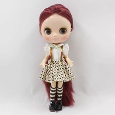 a doll with long red hair wearing a dress and black boots, standing against a white background