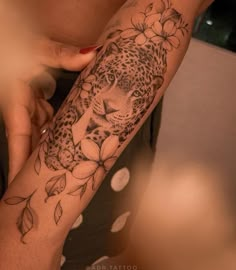 a woman's arm with a leopard and flowers tattoo on it