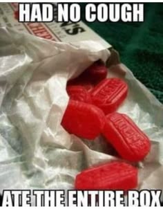 two red candies sitting in a bag with the caption had no cough ate the entire box