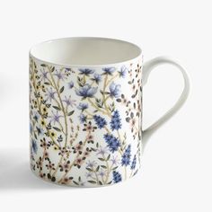 a coffee cup with blue and purple flowers on it's side, against a white background