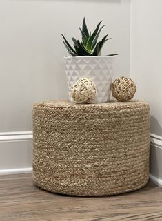 a plant sitting on top of a woven round stool next to a potted plant