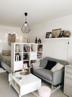 a living room filled with furniture next to a white table and bookshelf on top of a hard wood floor