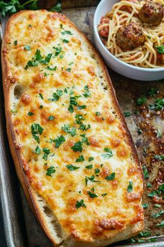 baked bread with cheese and meatballs on a baking sheet next to a bowl of spaghetti