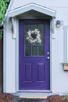 a purple front door with a wreath on it