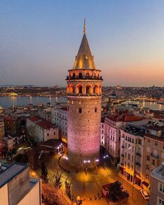 an aerial view of a city with a tower in the foreground and water behind it