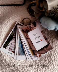 a bunch of cards sitting on top of a bed next to a bouquet and ring