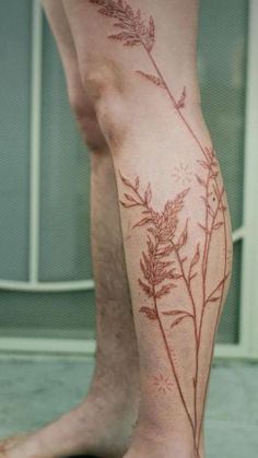 a person's leg with a plant tattoo on the lower part of their leg