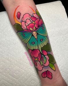 a woman's leg with a butterfly and flowers tattoo design on the left arm